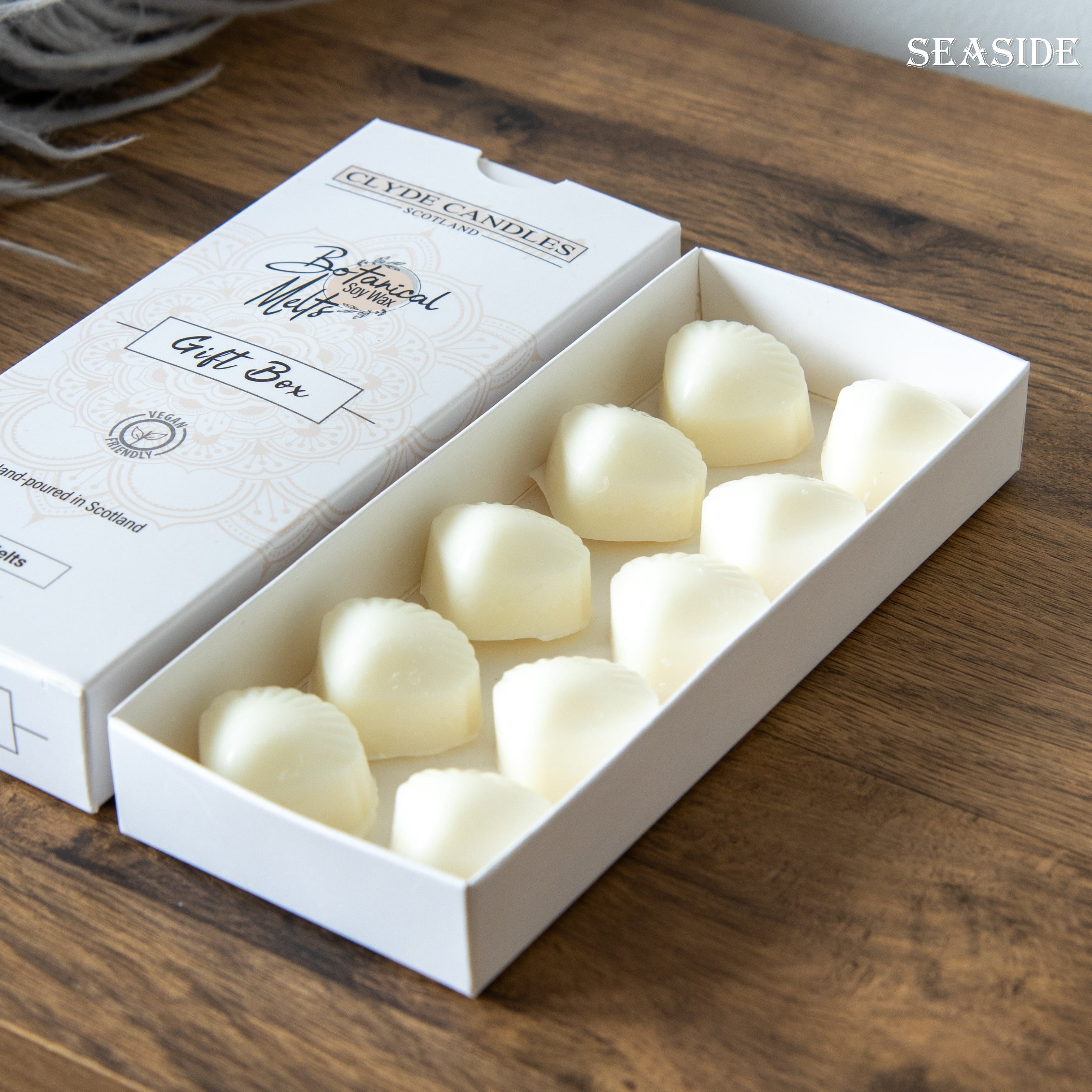 Box of white candles with a visible brand name on a wooden surface