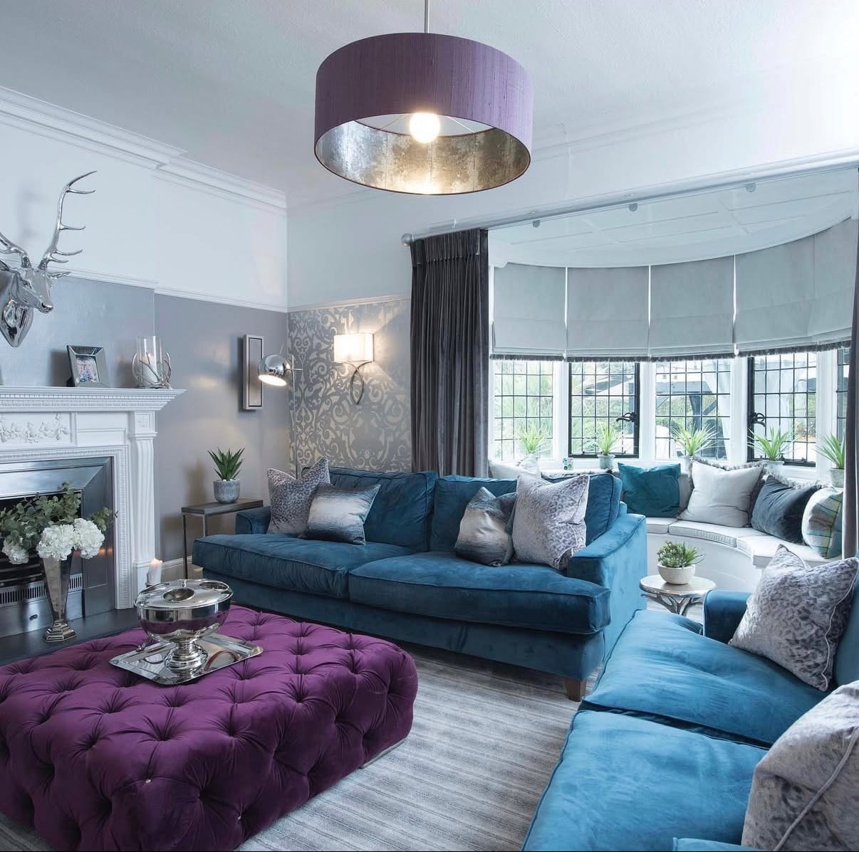 Modern living room with blue sofa, purple ottoman, and decorative elements.