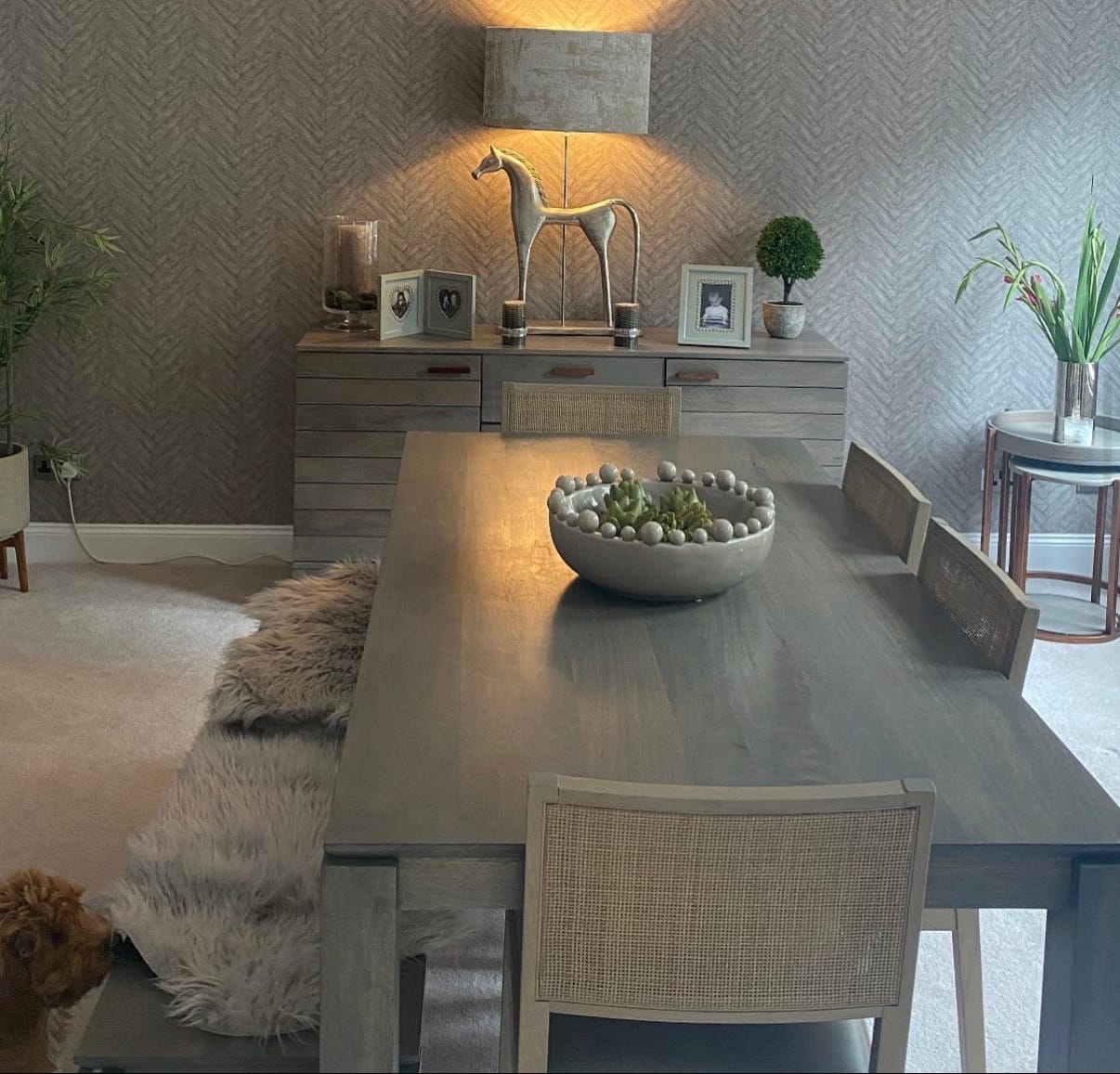 Dining room with a long table, chairs, and decorative items on a wall.