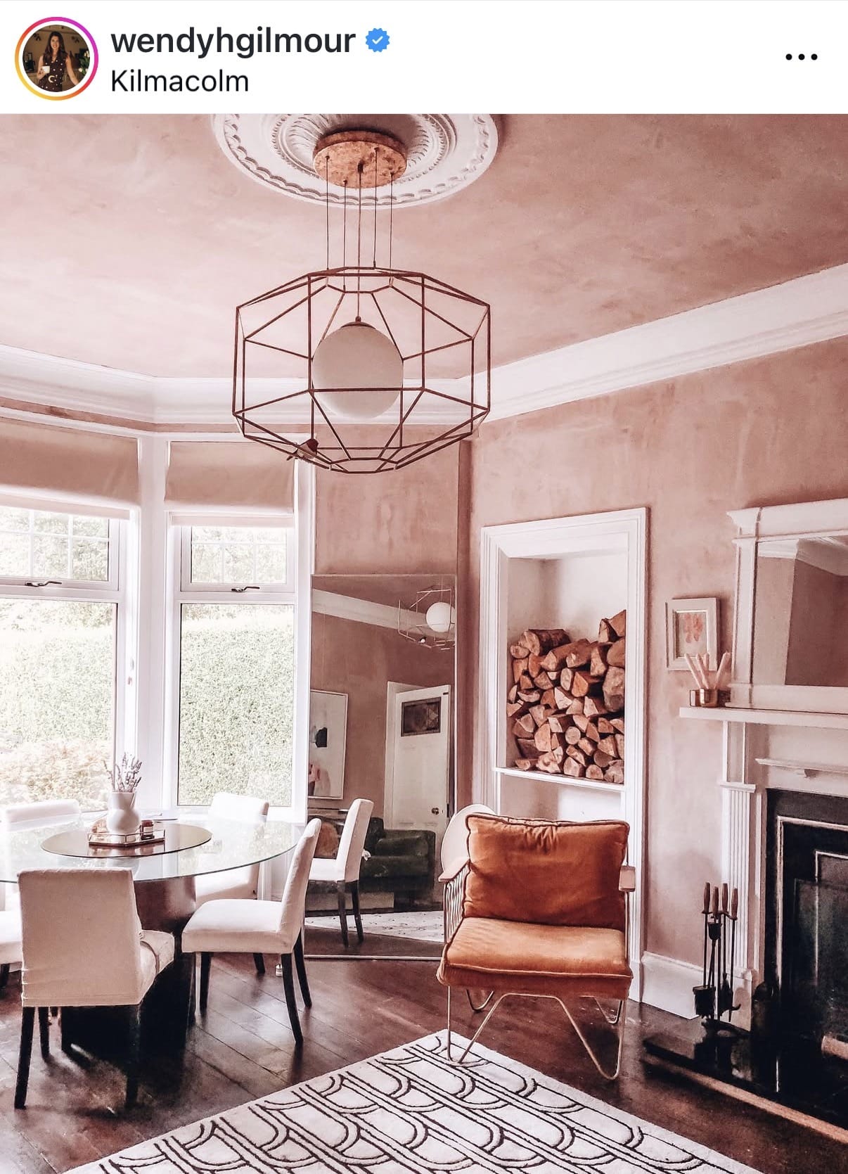 Modern living room with geometric chandelier, fireplace, and dining area.
