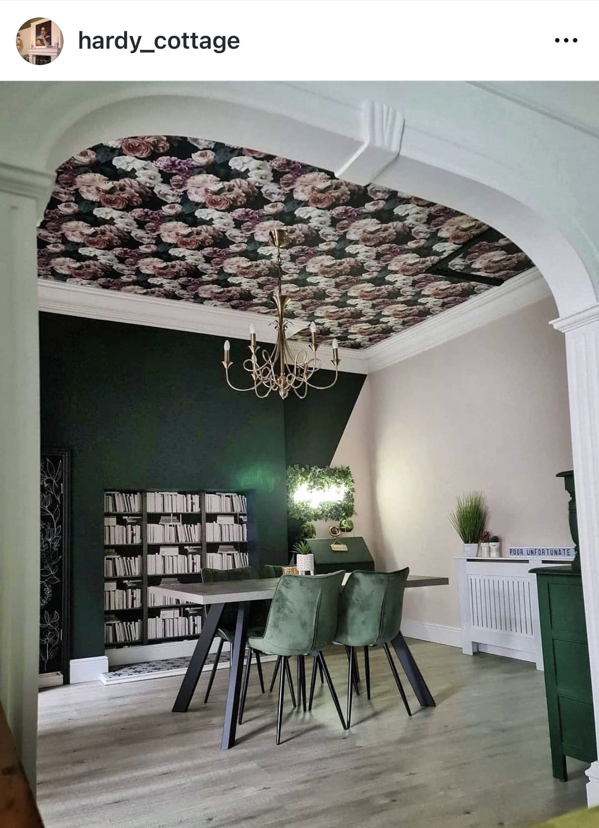 Dining room with floral ceiling design, bookshelf, and chandelier.