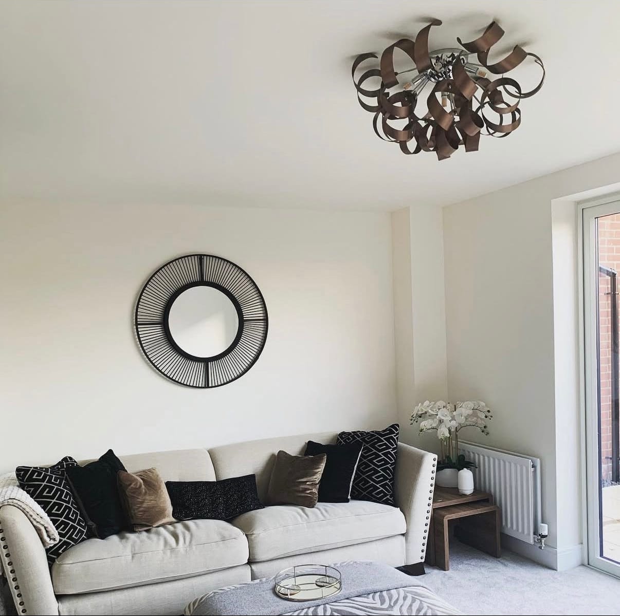 Living room with a white sofa, decorative pillows, and a modern chandelier.