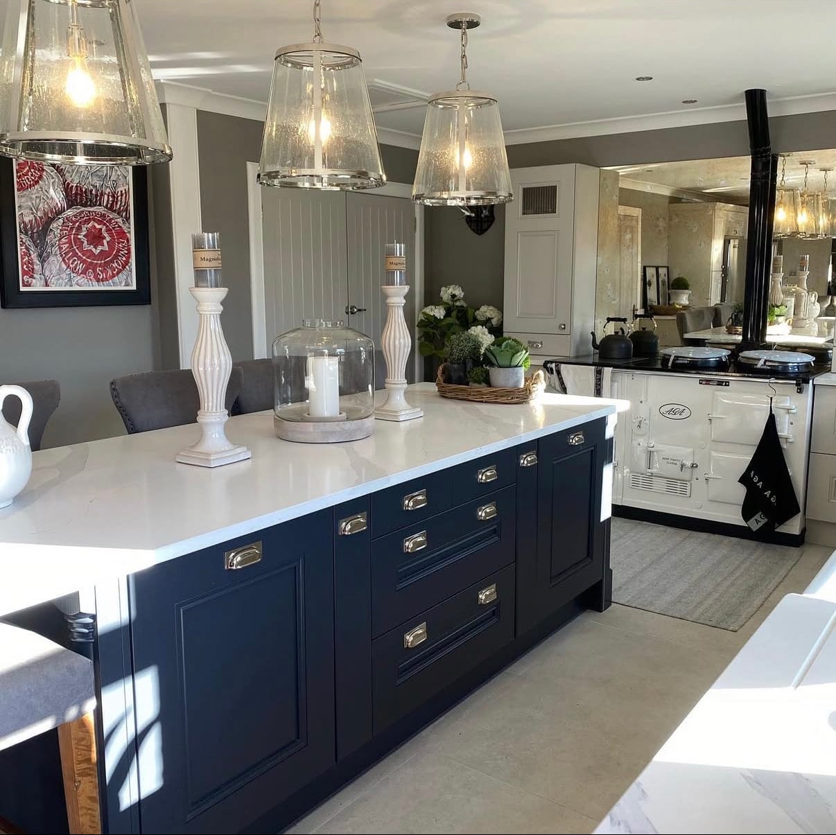 Modern kitchen with navy blue island and white countertops, featuring 'the_furniture_barn' branding.