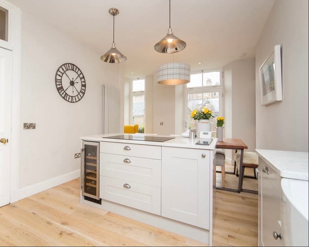 Modern kitchen with white cabinets and wooden flooring, featuring DCM Construction logo.