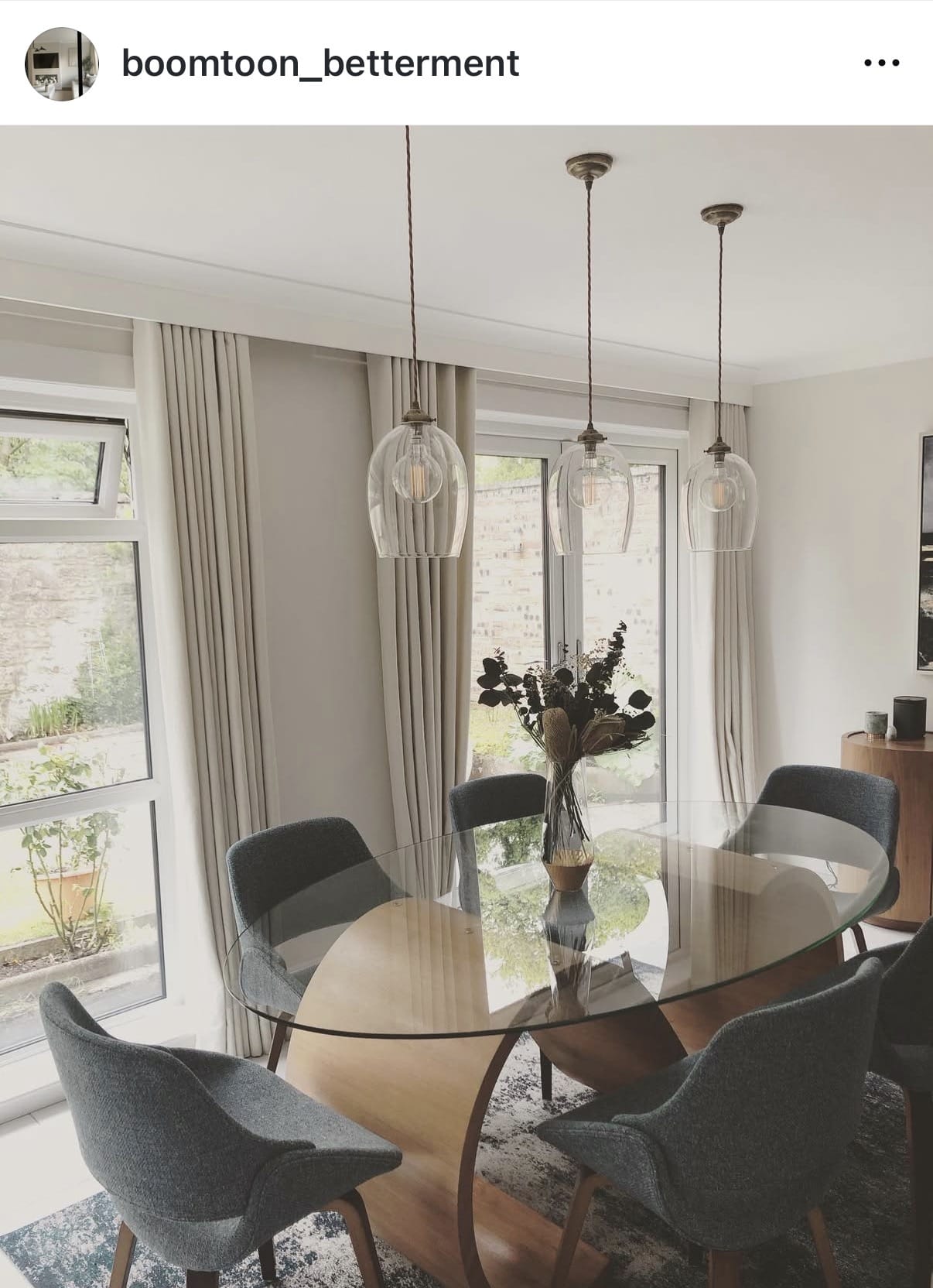 Modern dining room with a glass table and gray chairs, featuring a neutral color palette.