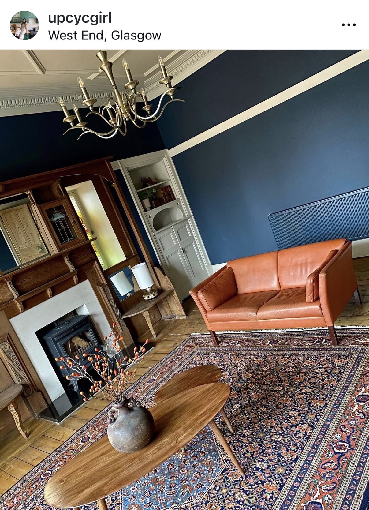 Living room with a brown leather sofa, wooden coffee table, and decorative elements.
