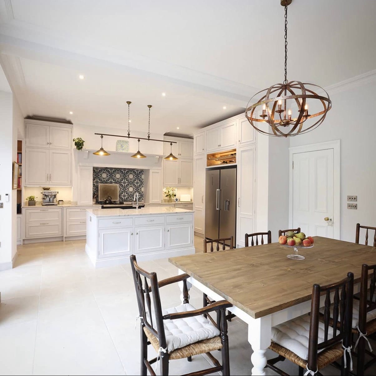 Modern kitchen with white cabinetry, wooden dining table, and decorative elements.