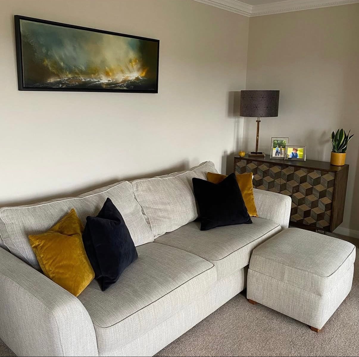 Living room with a beige sofa, ottoman, and decorative pillows.