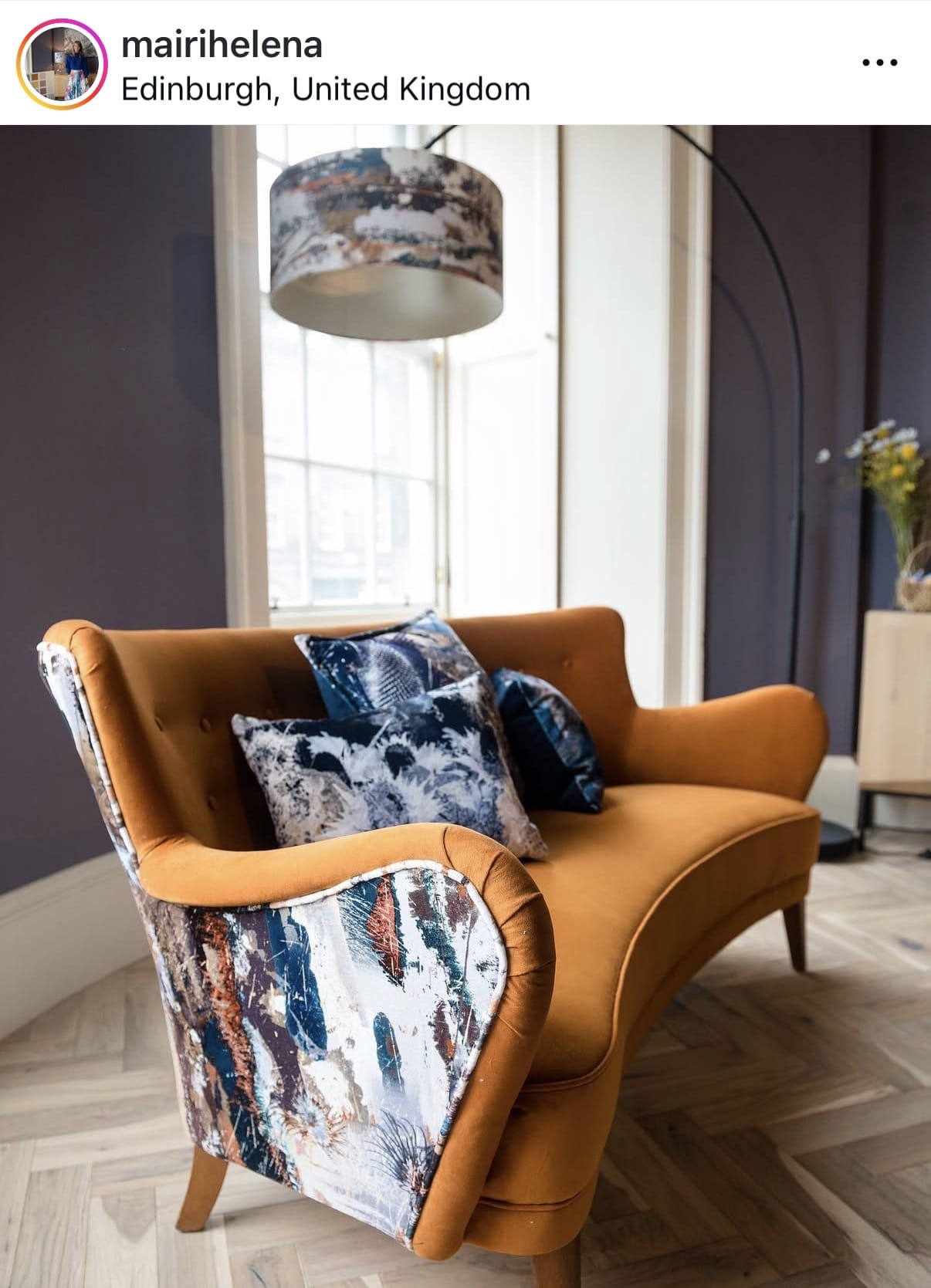 Orange sofa with patterned cushions in a room with large windows.