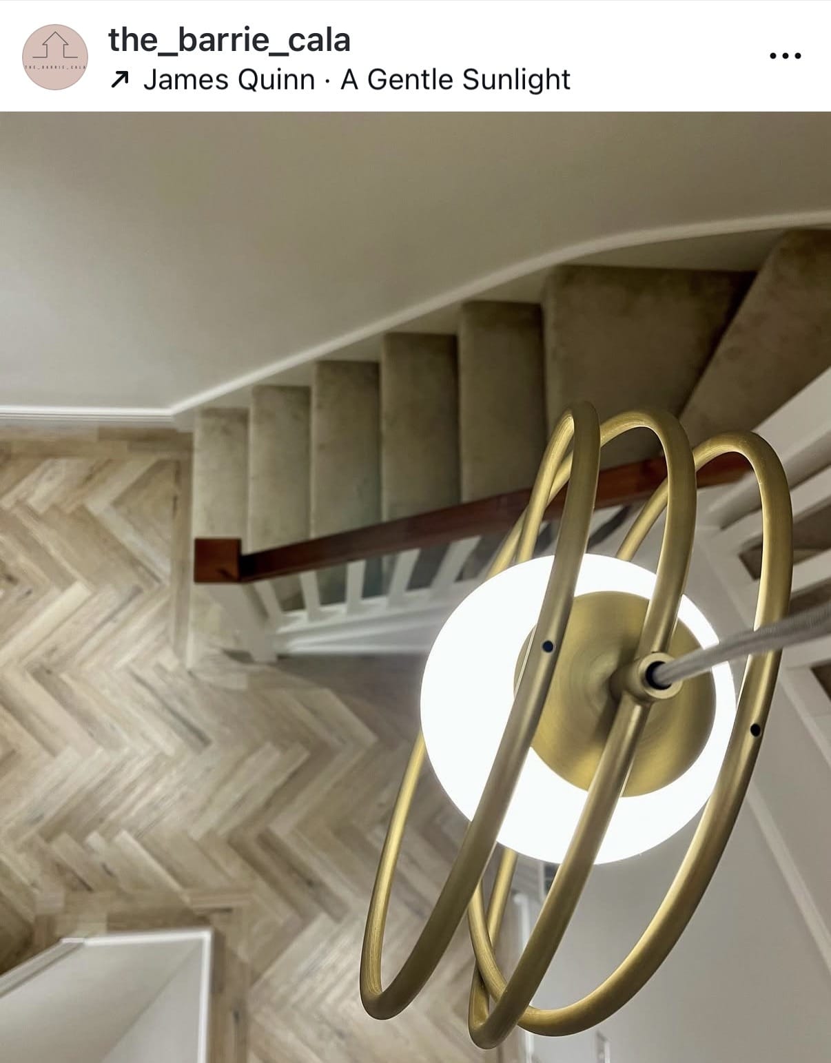 Modern ceiling light fixture in a room with a staircase and chevron patterned wall.