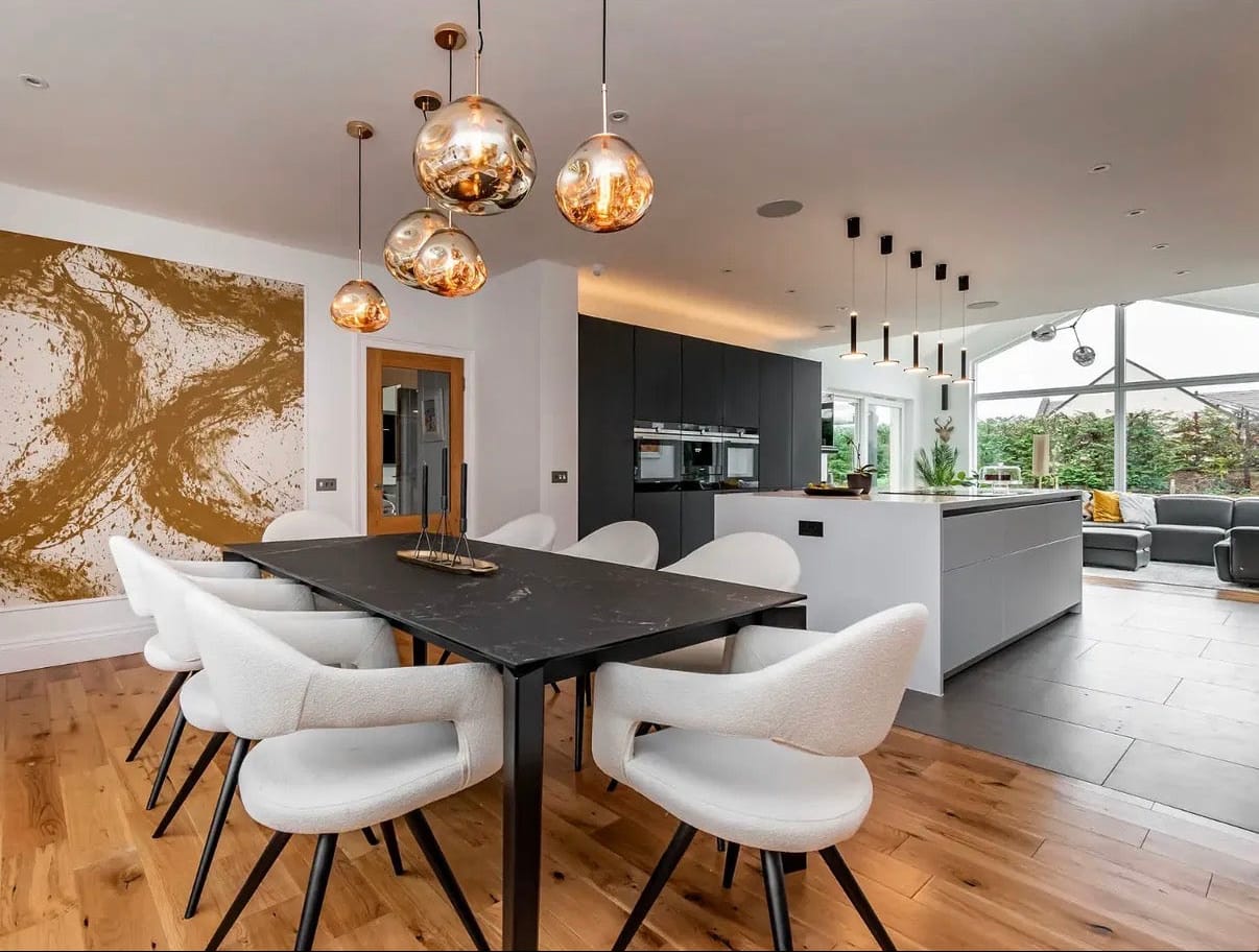 Modern kitchen and dining area with white chairs, black table, and pendant lights.
