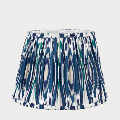 A tapered lampshade with a mushroom pleat design featuring a colorful blue ikat pattern.