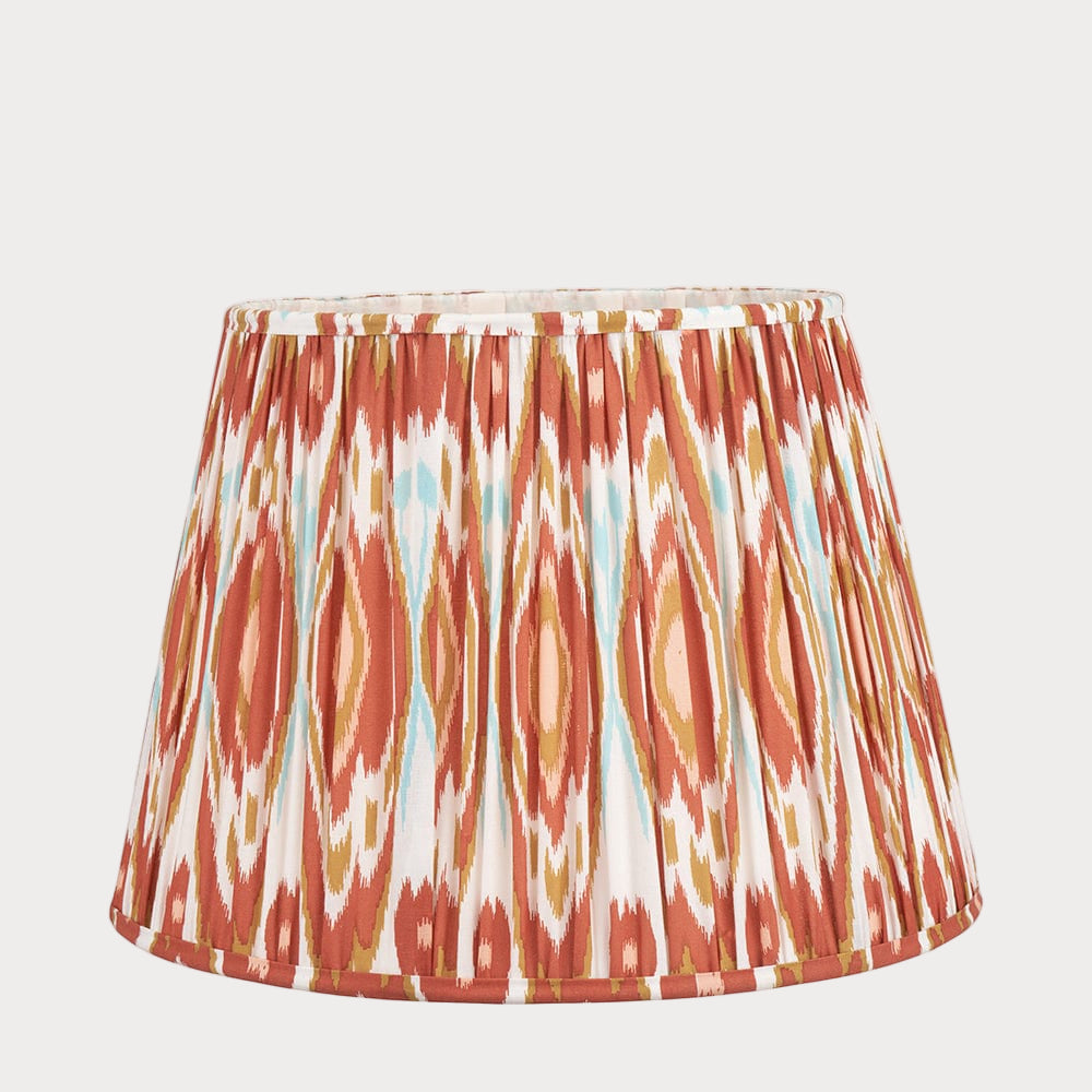 A conical cotton lampshade with a pleated design and an ikat pattern in cinnamon, apricot, and other colors.