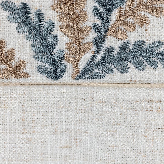Close-up of a textured fabric with floral patterns in brown and blue on a beige background