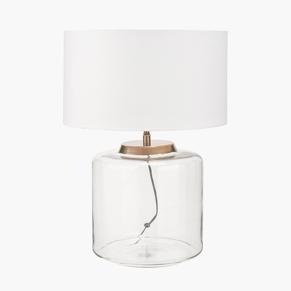 Table lamp with a clear glass base and white shade on a white background
