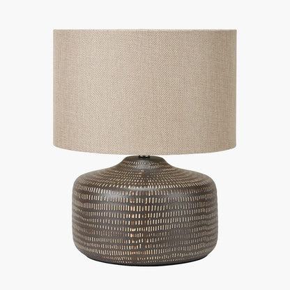 Table lamp with textured ceramic base and beige fabric shade on a white background