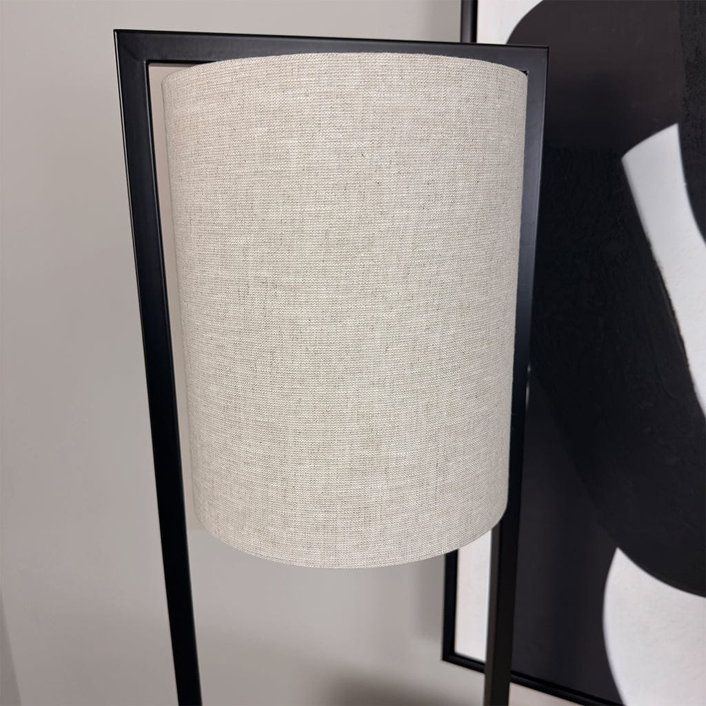 Floor lamp with a beige lampshade and black frame against a neutral background
