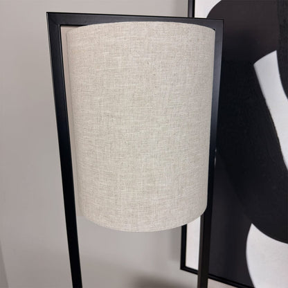 Floor lamp with a beige lampshade and black frame against a neutral background