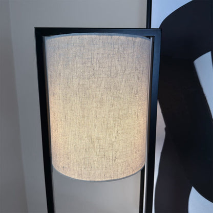 Floor lamp with a textured beige shade and black frame against a neutral background