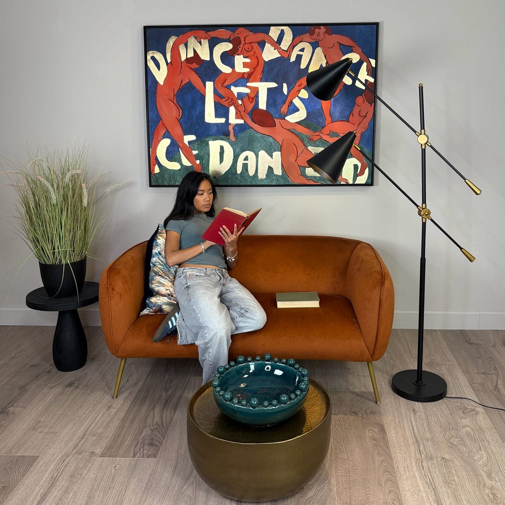 Woman reading a book on an orange sofa in a stylish living room with modern decor.