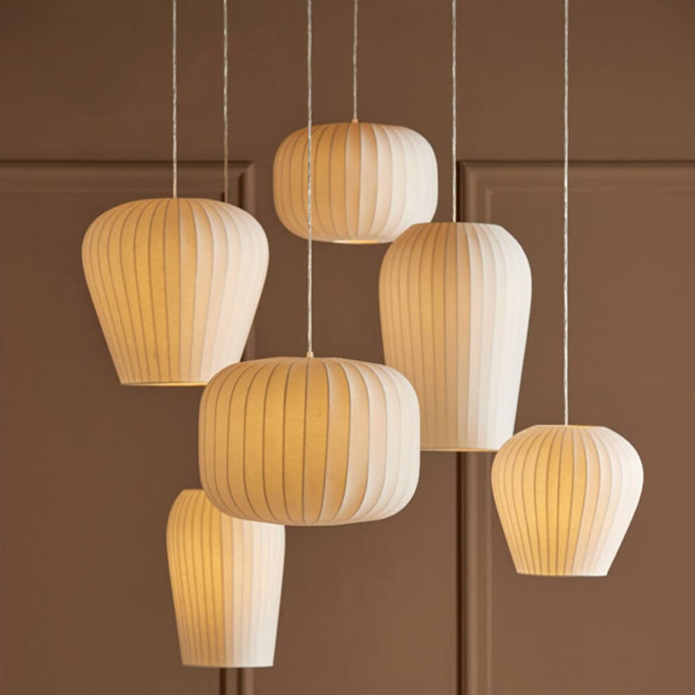 Set of pendant lights with parchment shades on a brown paneled wall.