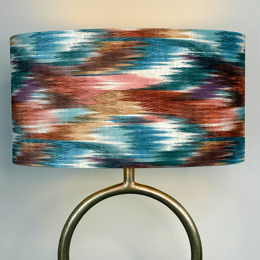 Lamp with a colorful, abstract-patterned shade on a plain background