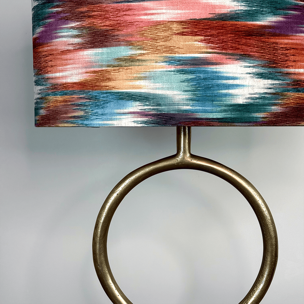 Lamp with a colorful, abstract-patterned shade and a metallic base on a gray background