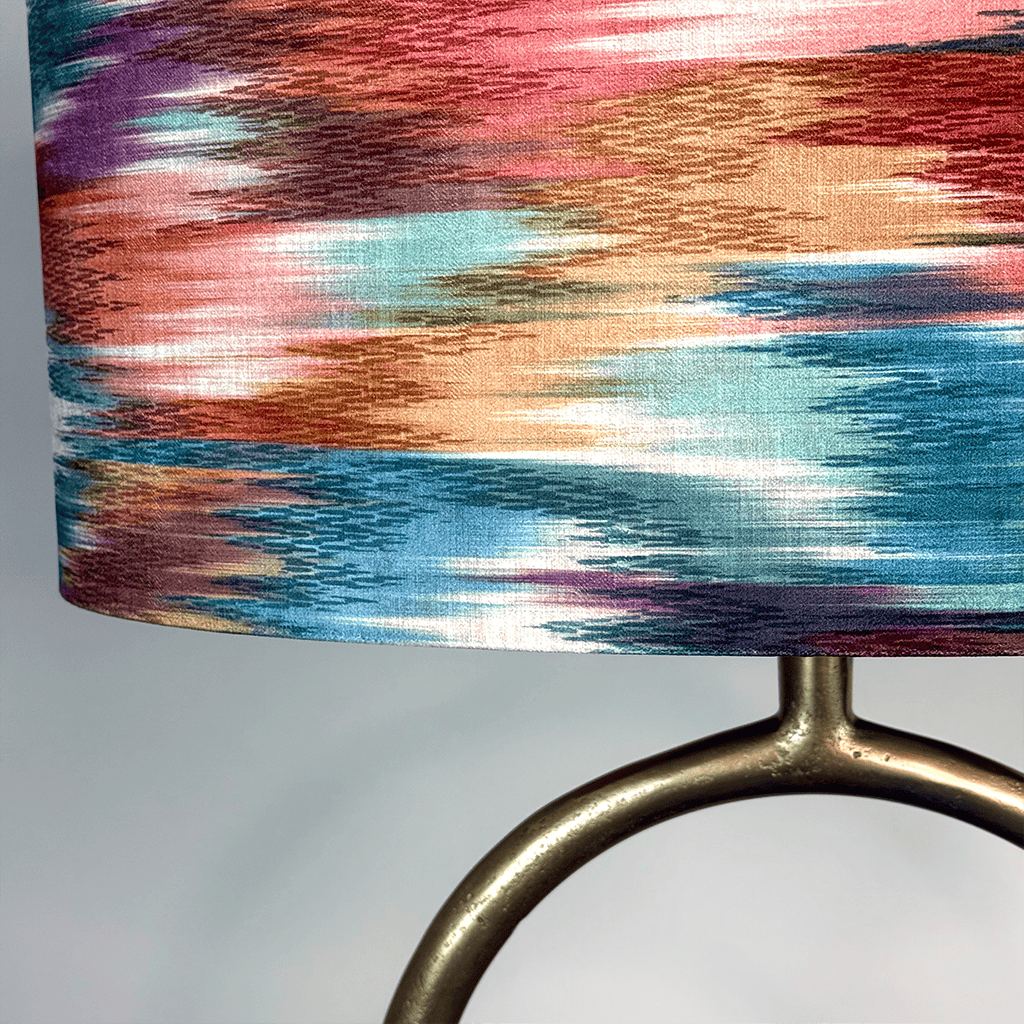 Lamp with a colorful, abstract-patterned shade on a plain background