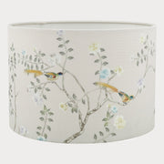 A cylindrical lampshade with a detailed floral and bird pattern on a beige background.