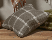 Plaid pillow on a wooden surface with a neutral background