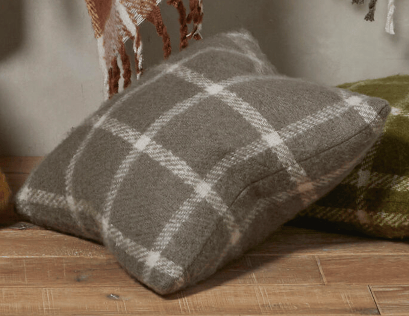 Plaid pillow on a wooden surface with a neutral background