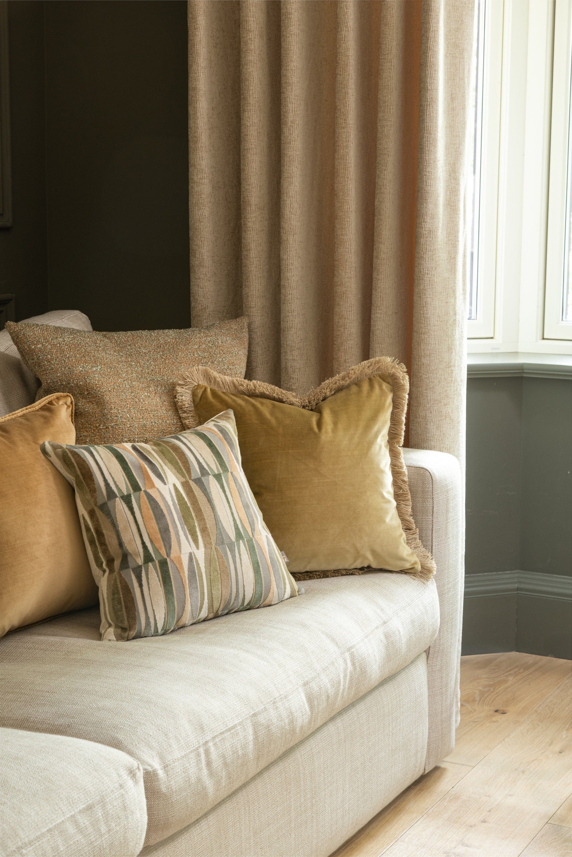 Beige sofa with patterned pillow against a neutral wall
