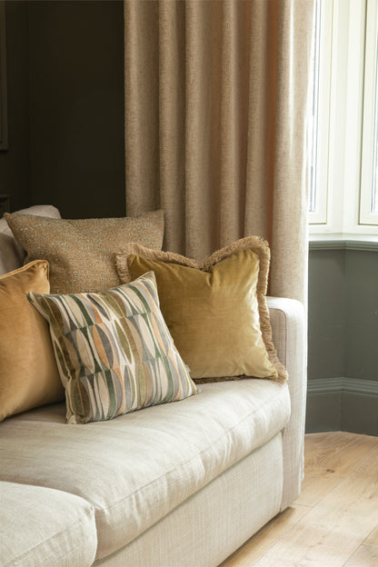Beige sofa with patterned pillow against a neutral wall