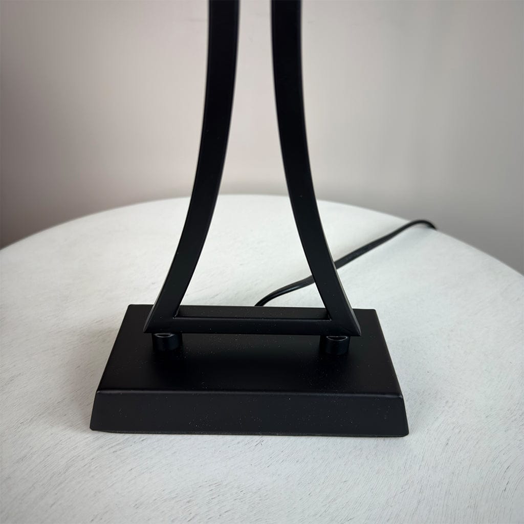 Black metal lamp base on a white surface with a neutral background