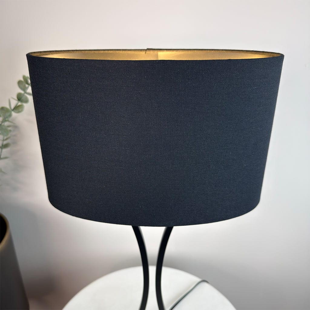Black lampshade on a white surface with a blurred background