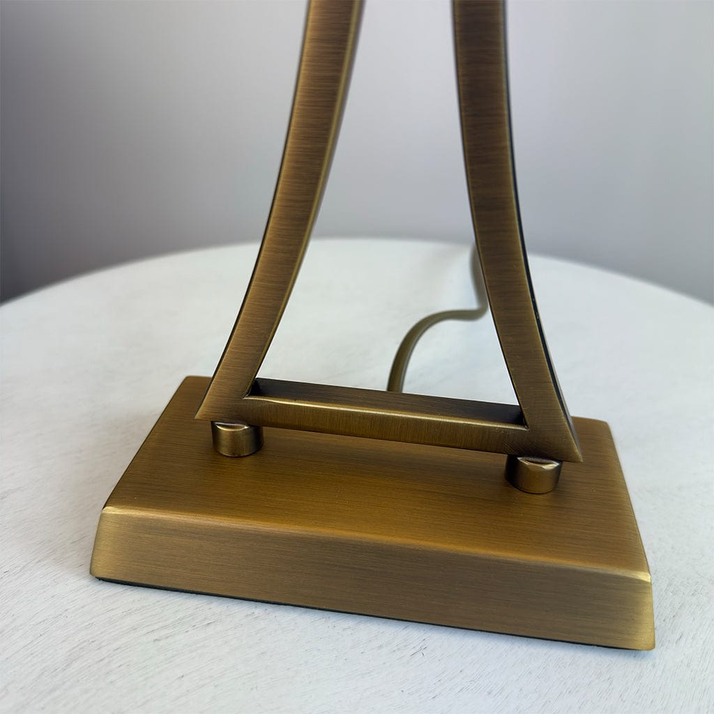 Bronze-colored lamp base on a white surface with a neutral background
