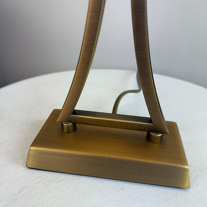 Bronze-colored lamp base on a white surface with a neutral background