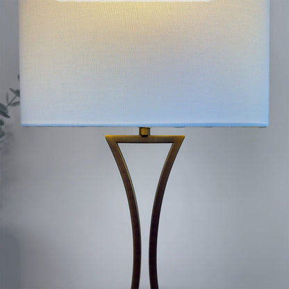 Floor lamp with a white shade and bronze base on a neutral background
