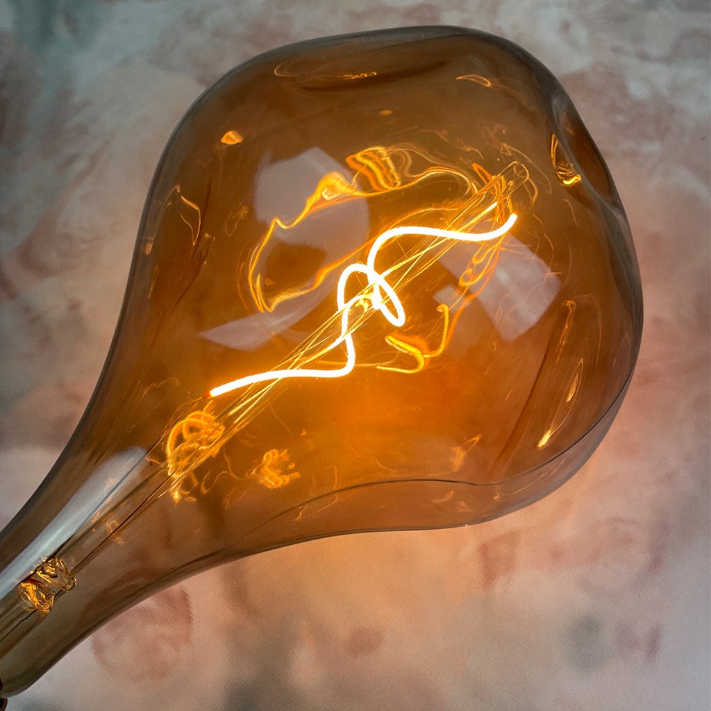 An E27 Organic XXL Natural LED Bulb with a smoked glass enclosure and visible filament inside lit against a marble background