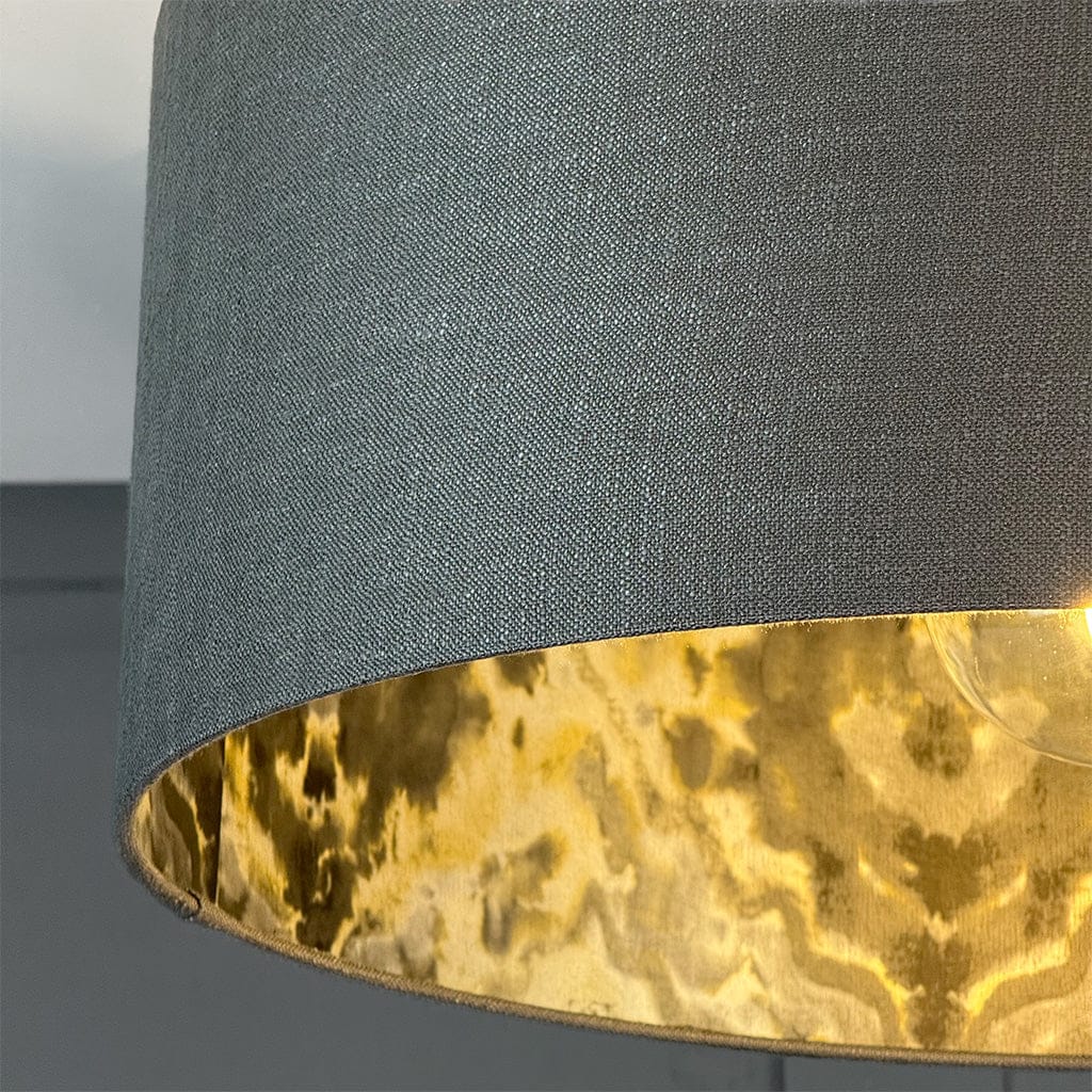 Close-up of a lampshade with a dark gray top and gold interior