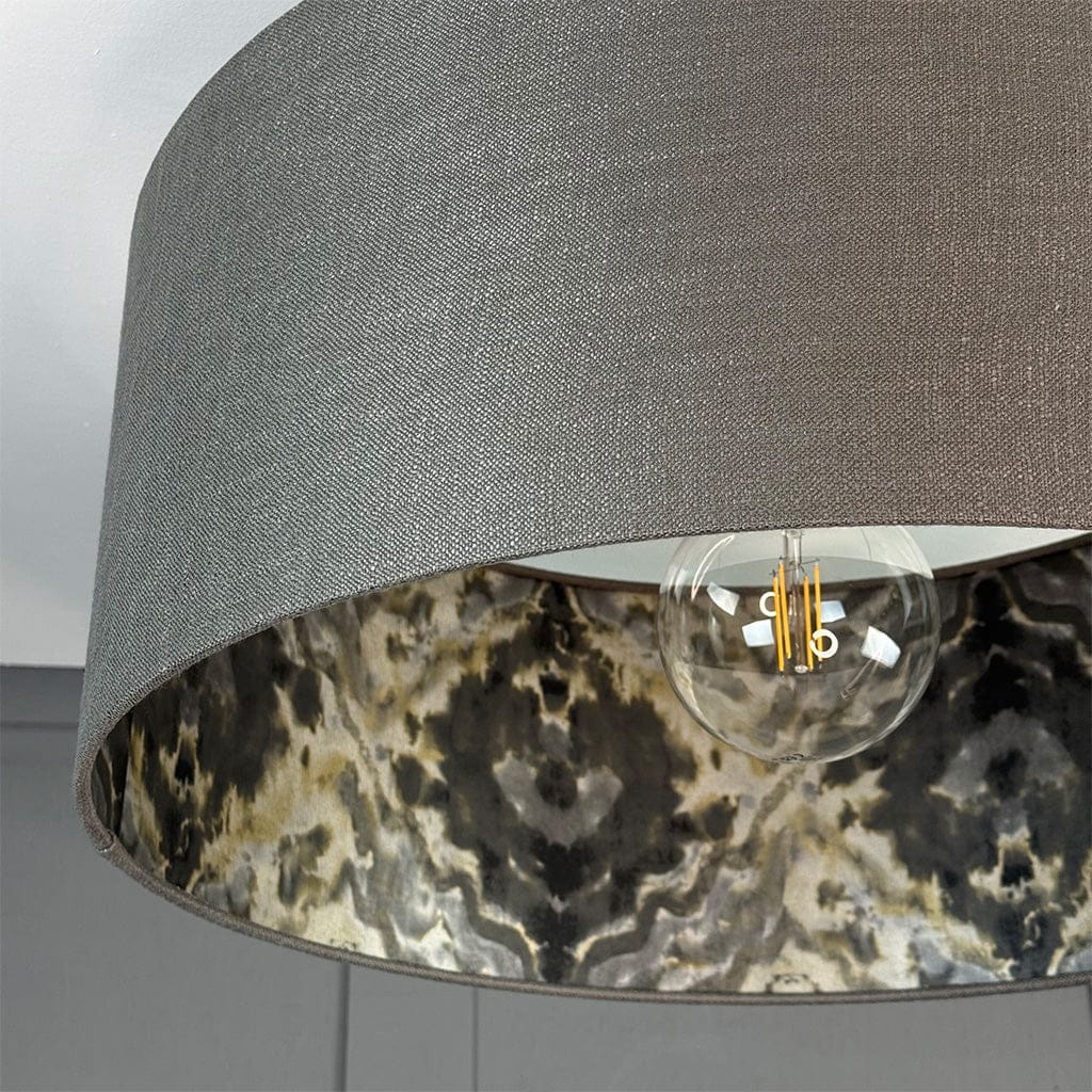 Close-up of a lamp with a gray shade and marble-patterned base.