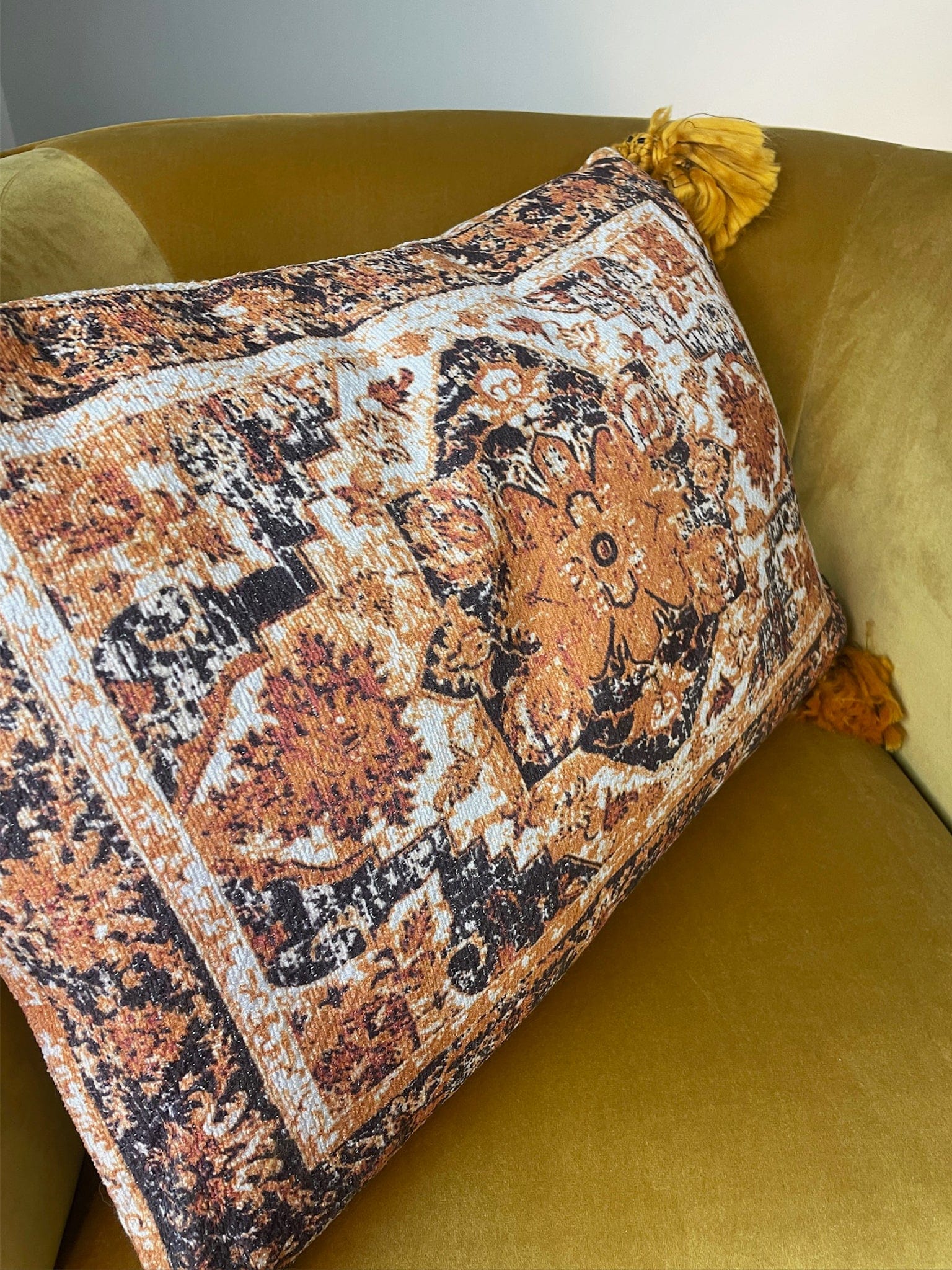 Decorative pillow with intricate patterns on a yellow sofa