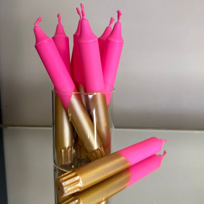 Pink and gold candles in a glass holder on a neutral background