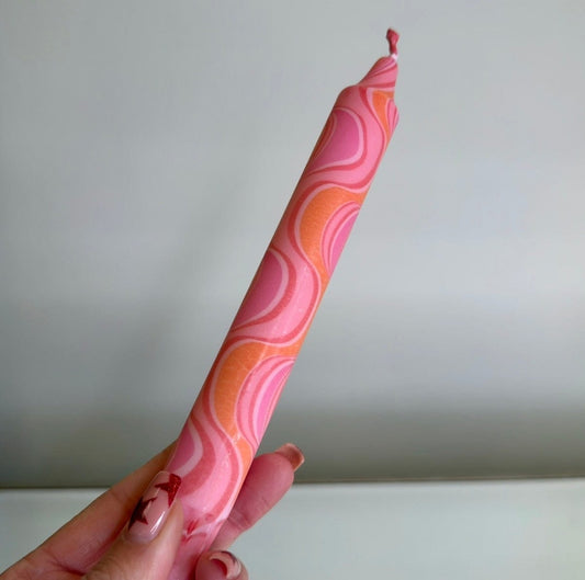 Hand holding a pink and orange patterned object against a plain background