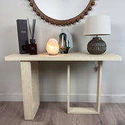 Wooden console table with decorative items against a plain wall