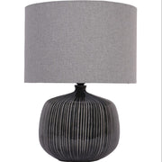 Table lamp with ribbed black base and gray fabric shade on a white background