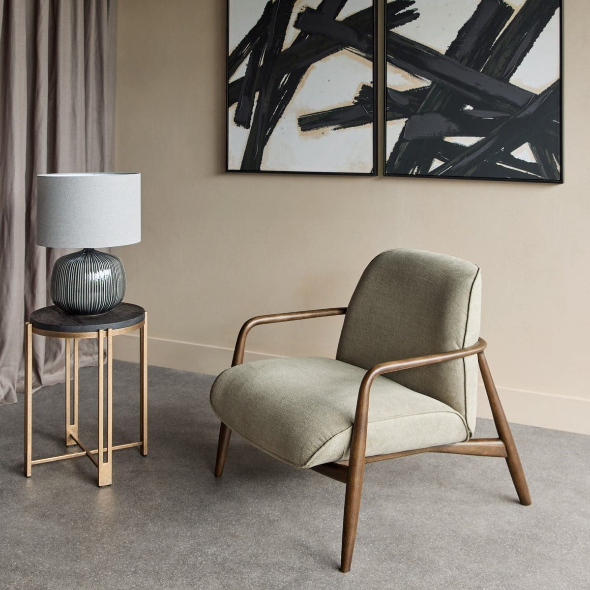Modern living room with a beige armchair, side table, and abstract wall art.