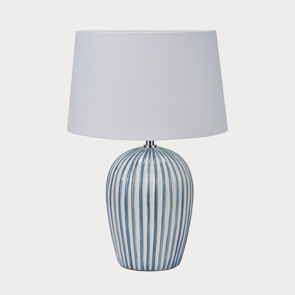 Table lamp with striped base and white shade on a white background