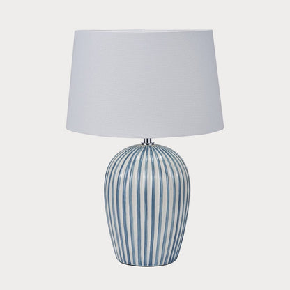 Table lamp with striped base and white shade on a white background