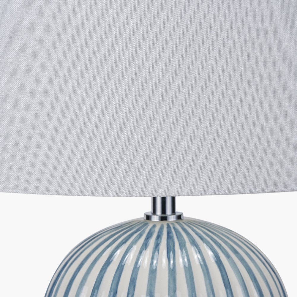 Table lamp with striped base and gray shade on a light gray background